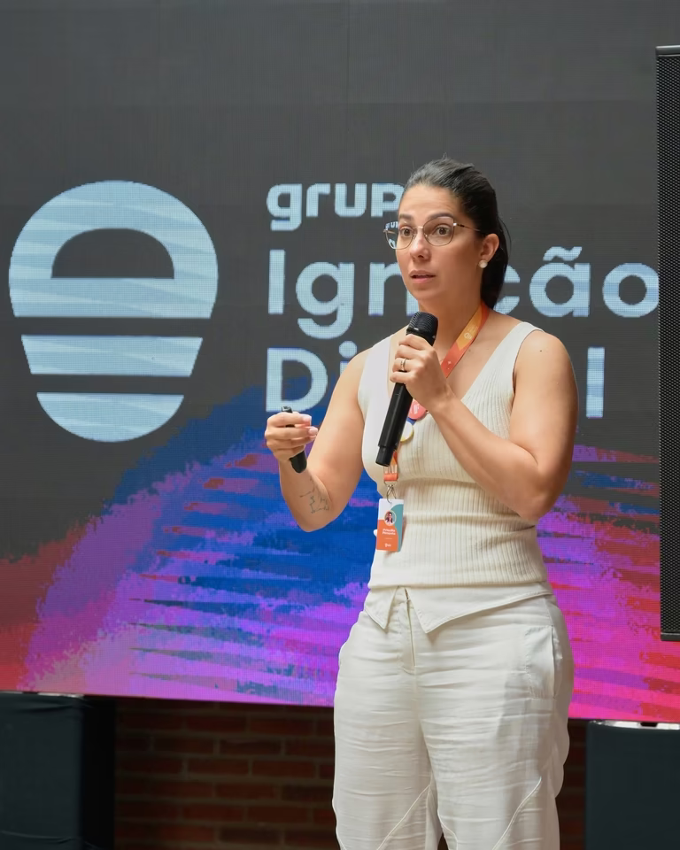Palestrante apresenta ao microfone em frente ao painel do Ignição Digital